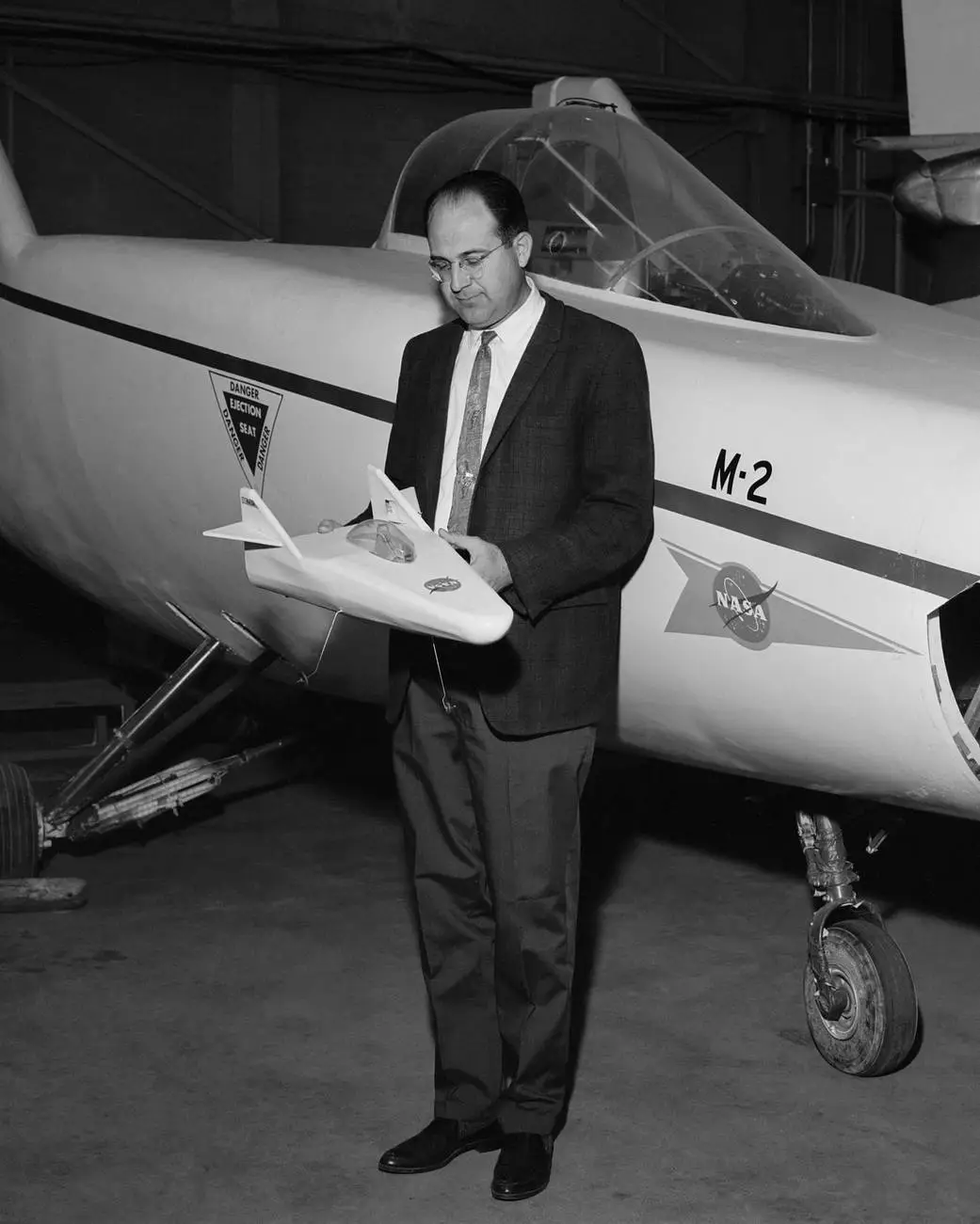 R. Dale Reed holding a model of the M2-F1 lifting body aircraft in front of the actual vehicle, 1967.